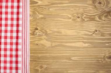 Checkered tablecloth on wooden table. Background with copy space. Horizontal.