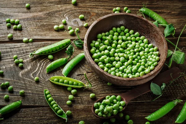 Délicieux pois verts mûrs couchés sur une table en bois. — Photo