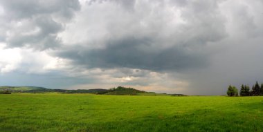 Yeşil çim ve fırtınalı bulut gökyüzü yukarıda dağlık manzara