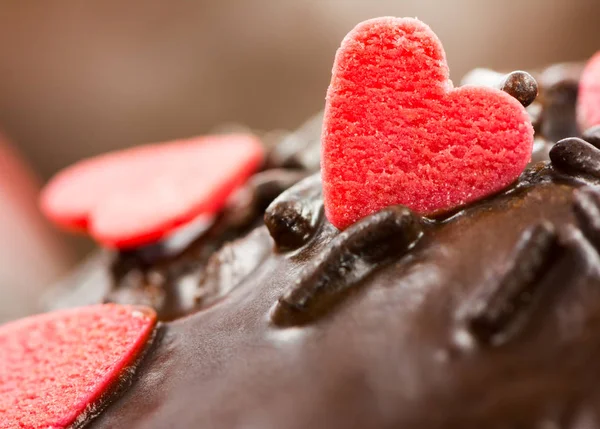 Detalhe de um queque de chocolate com corações de açúcar vermelho — Fotografia de Stock