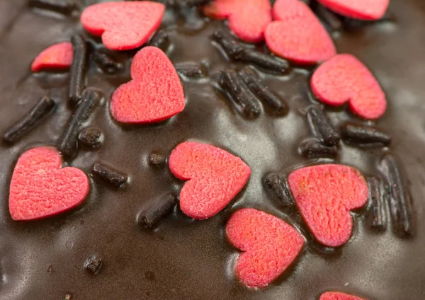 Detalhe de um queque de chocolate com corações de açúcar vermelho — Fotografia de Stock