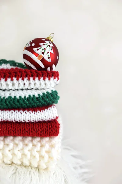 Une pile de crochet plié à la main et tricoter des vêtements avec une boule de Noël — Photo