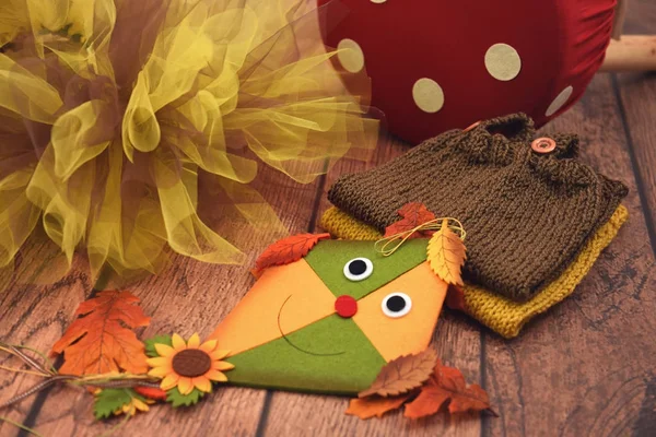 Toy kite, autumn leaves, tulle and knitted baby clothes — Stock Photo, Image