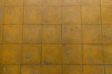 Sarı bir döşeme, eski ve aşınmış.