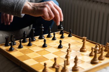 Satranç oynanıyor, tahtada tanınmayan bir adamın bir parçasının eliyle bir taşı oynattığı bir görüntü var.
