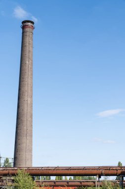 Duisburg Peyzaj Parkı 'ndaki terk edilmiş fırında mavi gökyüzüne karşı fabrika bacası.