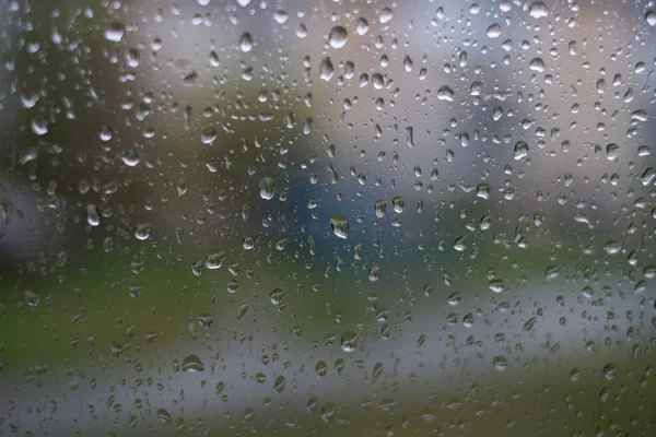 rain behind a window. rain drops on glass. cars on the road. heavy rain