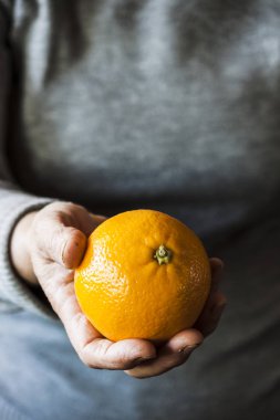 Bir portakal tutan bir kadın eli