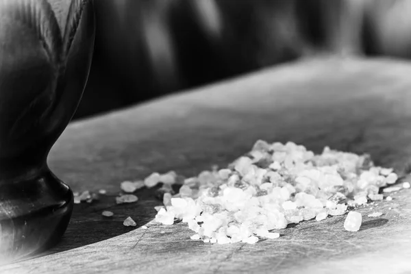 Thick grains of hymalayan salt and the pestle to grind it - black and white