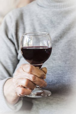 Bir bardak kırmızı şarap tutan el kadındır