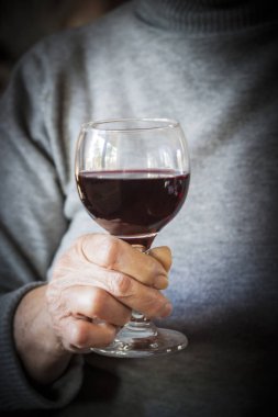 Bir bardak kırmızı şarap tutan el kadındır