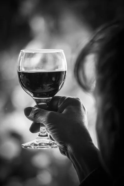 Woman is holding high a glass of red wine - black and white image — Stock Photo, Image
