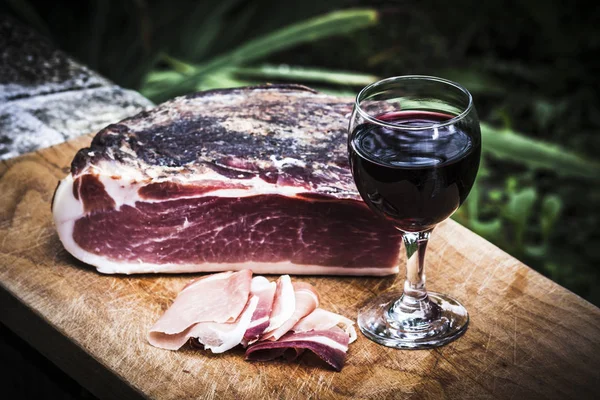 Speck italiano com vinho tinto na bandeja de madeira no jardim — Fotografia de Stock