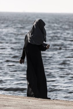 Genç Müslüman kız deniz kenarında yürüyüş
