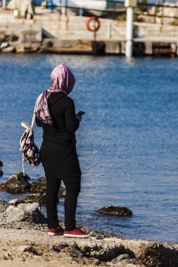 Deniz kenarında telefon kullanan Müslüman Genç kadın