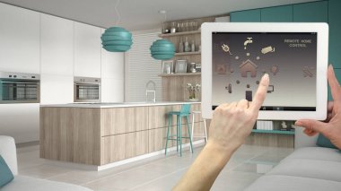 Akıllı uzaktan ev kontrol sistemi dijital tablet. Aygıt app simgeleri ile. İç mimari tasarım arka planda modern turkuaz ve ahşap mutfak.