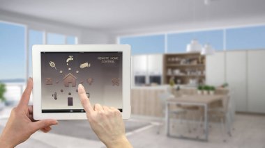 Akıllı uzaktan ev kontrol sistemi dijital tablet. Aygıt app simgeleri ile. Bulanık iç mimari tasarım arka planda modern mutfak