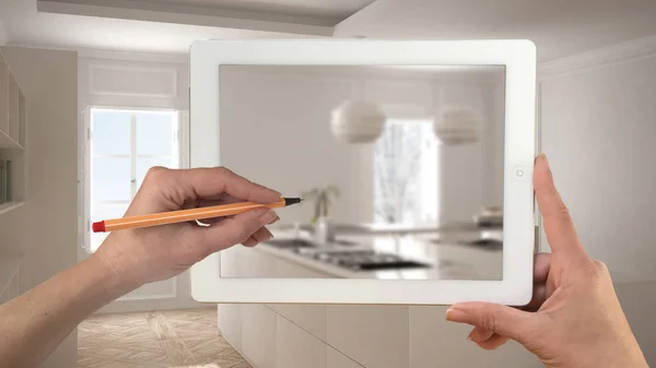 Kéz, gazdaság, és a rajz a tabletta találat homályos modern konyha. Igazi kész minimalista fehér és fa konyha a háttérben, építészet, belsőépítészet bemutatása — Stock Fotó