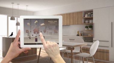 Akıllı uzaktan ev kontrol sistemi dijital tablet. Aygıt app simgeleri ile. İç mimari tasarım arka planda minimalist beyaz ve ahşap mutfak