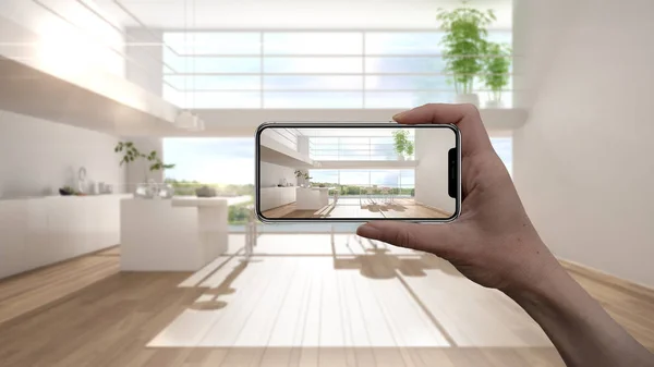 Hand holding smart phone, AR application, simulate furniture and interior design products in real home, architect designer concept, blur background, modern white and wooden kitchen