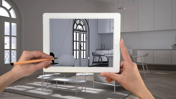 Hände halten und zeichnen auf einem Tablet, das eine klassische weiße Küche mit Wohnzimmerdetails zeigt. echtes fertiges Interieur im Hintergrund, Architekturdesign-Präsentation — Stockfoto