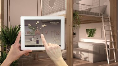 Dijital tablette akıllı uzaktan kumanda sistemi. Uygulama simgeleri olan aygıt. Stüdyo daire, tavan arası yatak, asma kat, salıncak. Kanepeli bir oda, mimari iç tasarım.