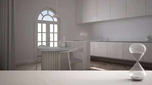 Biały stół lub półka z kryształową klepsydrą mierzącą czas mijania nad minimalistyczną klasyczną kuchnią z wyspą i krzesłami, architektoniczny wystrój wnętrz, tło przestrzeni do kopiowania — Zdjęcie stockowe
