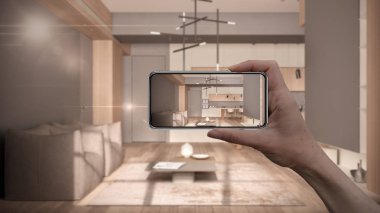 El ele tutuşan akıllı telefon, Ar uygulaması, gerçek evde mobilya ve iç tasarım ürünleri simülasyonu, mimar tasarım konsepti, bulanık arka plan, minimalist mutfak ve oturma odası