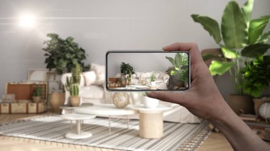 El ele tutuşan akıllı telefon, AR uygulaması, gerçek evde mobilya ve iç tasarım ürünleri simülasyonu, mimar tasarım konsepti, bulanık arka plan, eski tarz oturma odası
