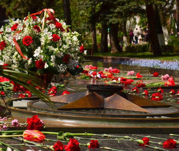 Eternal flame memorial to fallen defenders with carnations around 9 may