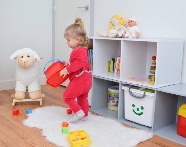 Beyaz çocuk odasında oyuncaklarla oynayan kız