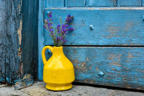 Lavanda en un jarrón amarillo sobre un fondo de la puerta azul de mala calidad —  Fotos de Stock