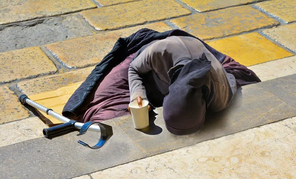 Merdivenlerde yalan sadaka için yalvarıyor bir koltuk değneği ile siyah giysili bir kadın