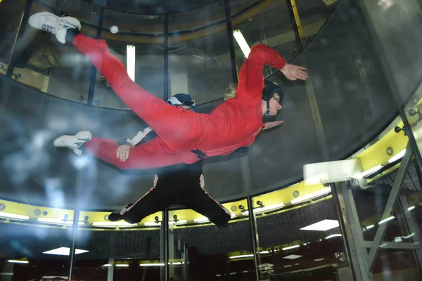A woman and an instructor climb up in an air tube with glass walls