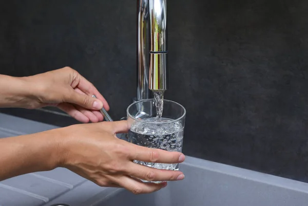 Kobiecej ręki nalewa wody do szklanki — Zdjęcie stockowe