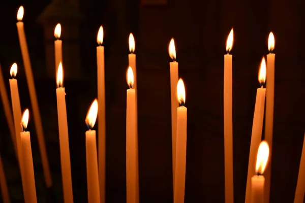 Beaucoup de bougies de l'église sur fond noir — Photo