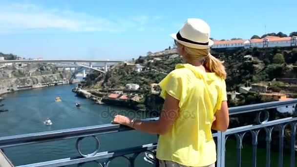 Menina loira fica na ponte e olha para o rio — Vídeo de Stock