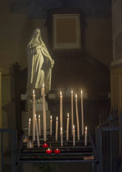 En massa ljus och staty av Jungfru Maria i en kyrka — Stockfoto