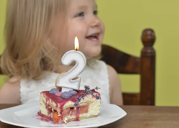 Cut slice of birthday cake 2 years for Small girl — Stock Photo, Image