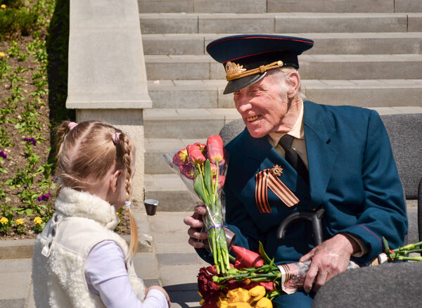 PYATIGORSK, RUSSIA - MAY 09, 2011: Girl gives flowers to veteran on Victory Day.