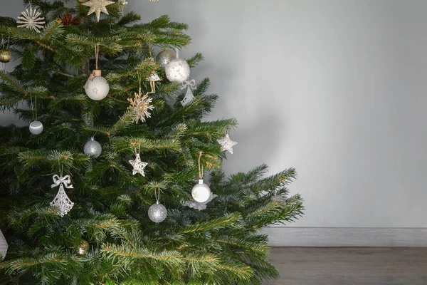 Χριστουγεννιάτικο δέντρο διακοσμημένο με παιχνίδια κοντά σε γκρίζο τοίχο — Φωτογραφία Αρχείου