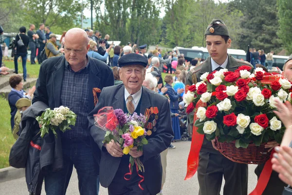 PYATIGORSK, RUSSIA - MAY 09, 2017: Young carer and elderly man with a walking stick on Victory Day Royalty Free Stock Images