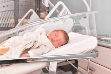 Yeni doğmuş bebek hastane yatağında uyuyor.