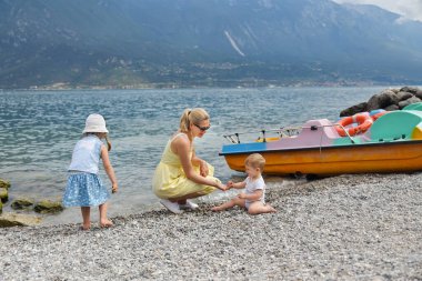 Çocuklu genç bir anne Garda Gölü kıyısında dinleniyor.