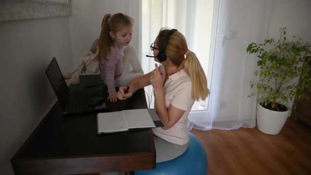 Matka Siedzi Piłce Fitness Słuchawkach Pracuje Domu Córką Podczas Kwarantanny — Wideo stockowe