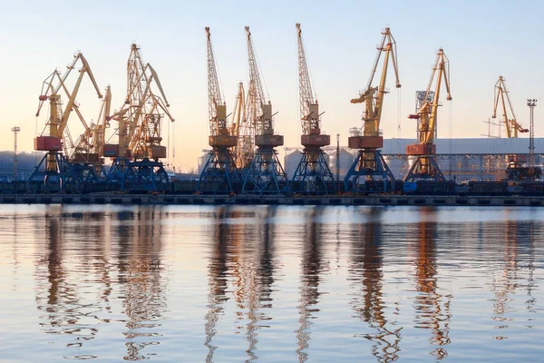 Odessa, Ukraine - 02. Januar 2017: Containerkräne im Terminal des Frachthafens, Frachtkräne spiegeln sich im Wasser. Sonnenuntergang lizenzfreie Stockbilder