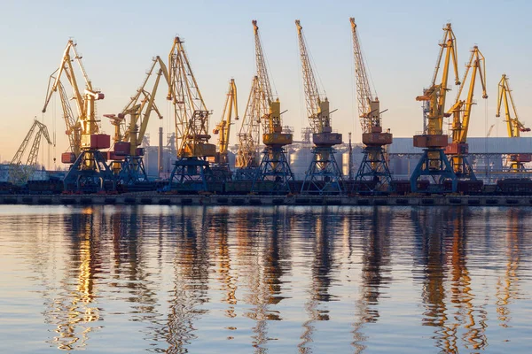 Odessa, Ukraine - 02. Januar 2017: Containerkräne im Terminal des Frachthafens, Frachtkräne spiegeln sich im Wasser. Sonnenuntergang Stockbild