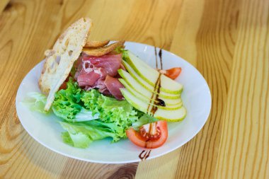 İtalyan salatası prosciutto jambonu, marul, peynir ve elma, güzel bir eski ahşap masaya servis. Seçici odak