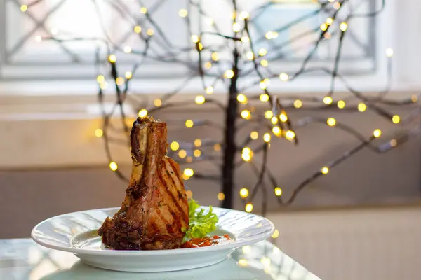 En vacker saftig Fläskstek med ben tillagas på grillen serveras på vit platta med en vacker bakgrund — Stockfoto