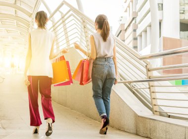 iki genç kadın alışveriş çantası, tüketim ve insanlar kavramı tutan el ile alışveriş için yürüyüş.
